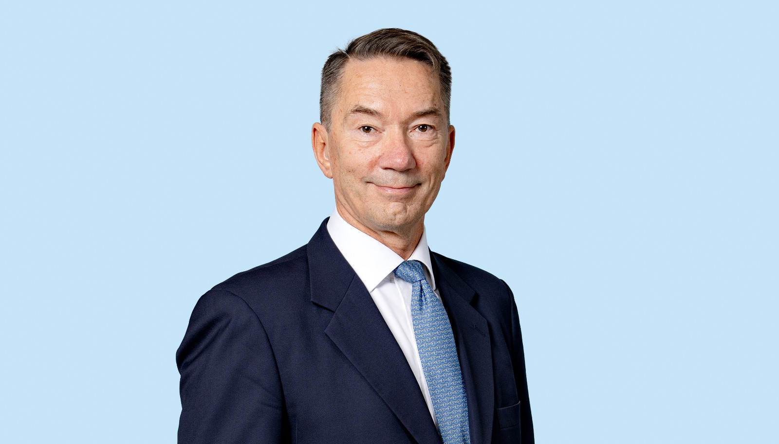 Mies puku päällä katsoo kameraan