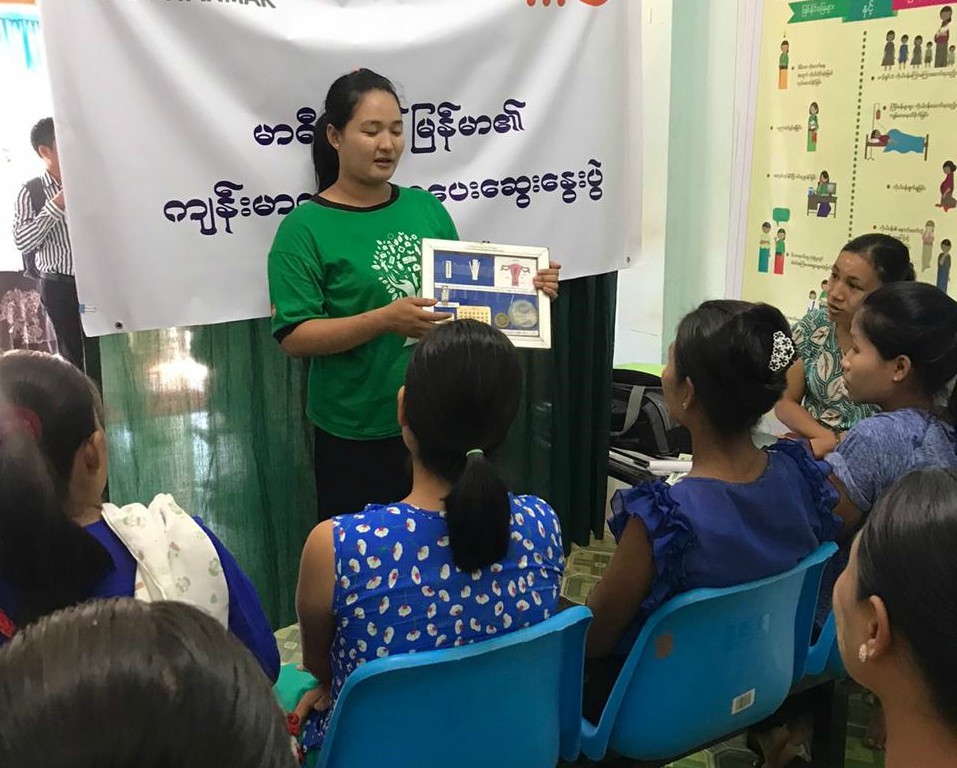 A woman is giving a lecture about sexual and reproductive health to a group of women in Myanmar.