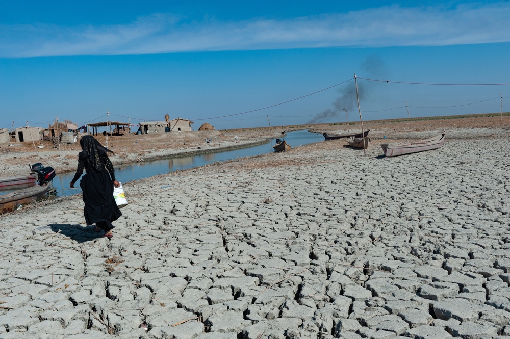 Nainen kerää vettä kuivuneella suoalueella Etelä-Irakissa. Kuva: John Wreford/ Shutterstock