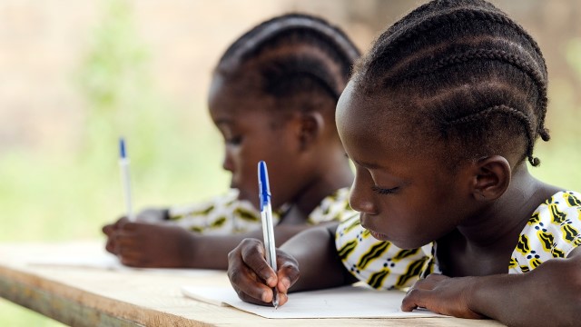 Afrikkalaiset lapset koulussa kirjoittamassa.