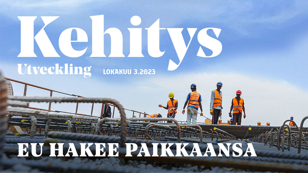 Kehitys-Utveckling-lehden kansikuva, jossa raknennustyöntekijät seisovat keskeneräisen talon katolla.