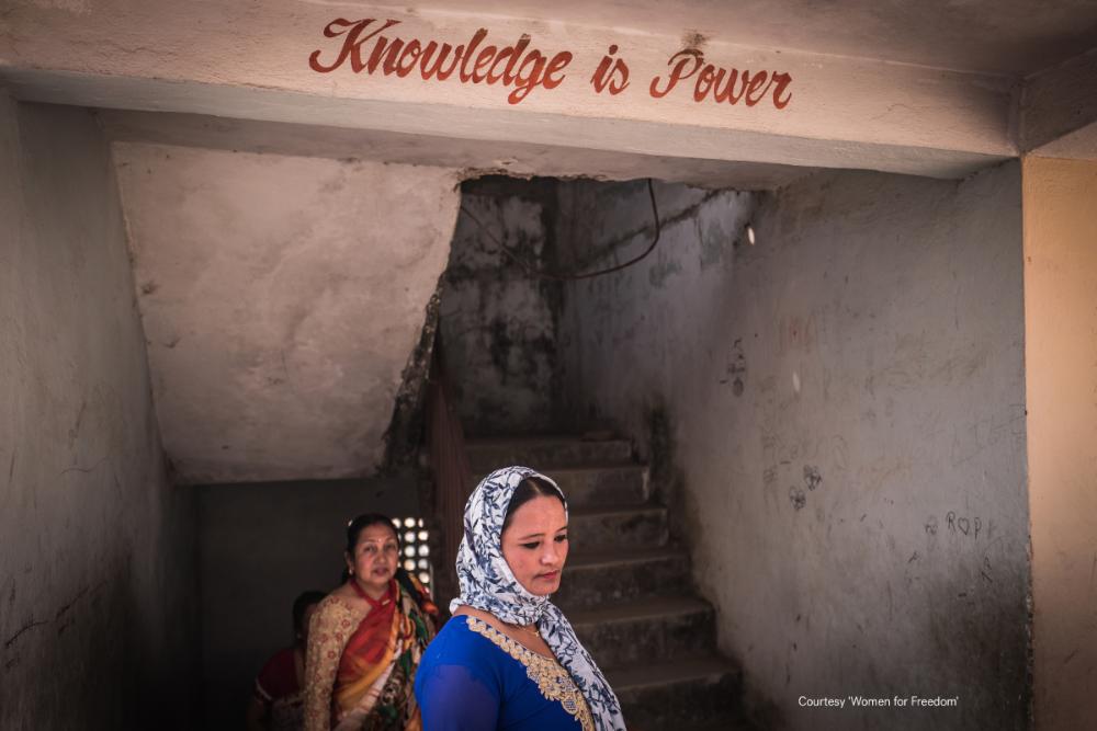 Kaksi naista porraskäytävässä. Kuvan yläreunassa lukee "Knowledge is power".
