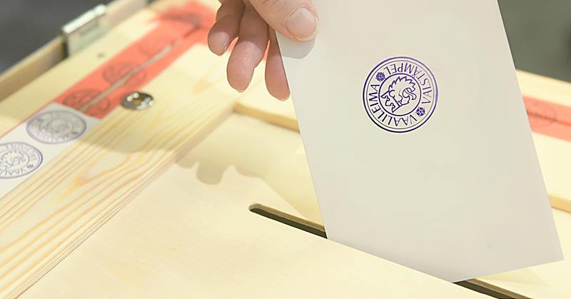 Kuvassa käsi, joka laittaa äänestyslipuketta vaaliuurnaan.