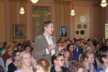 En lärare från Vasa övningsskola ställer en fråga till ministrarna. Festsalen är fullsatt.