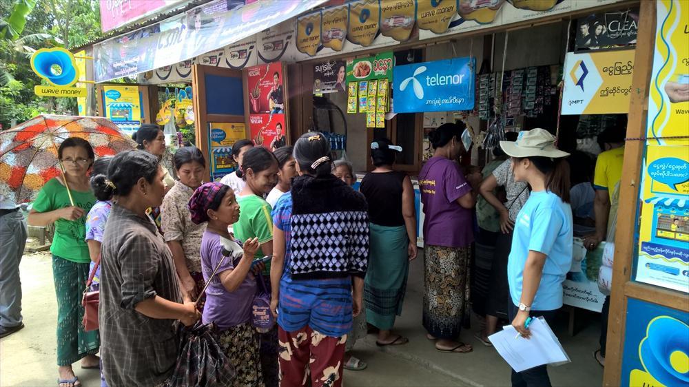 Humanitaarisen avun saajat nostavat käteistä matkapuhelimen avulla Myitktyinan kaupungissa koillisessa Myanmarissa. Kuva: Claus Lindroos.