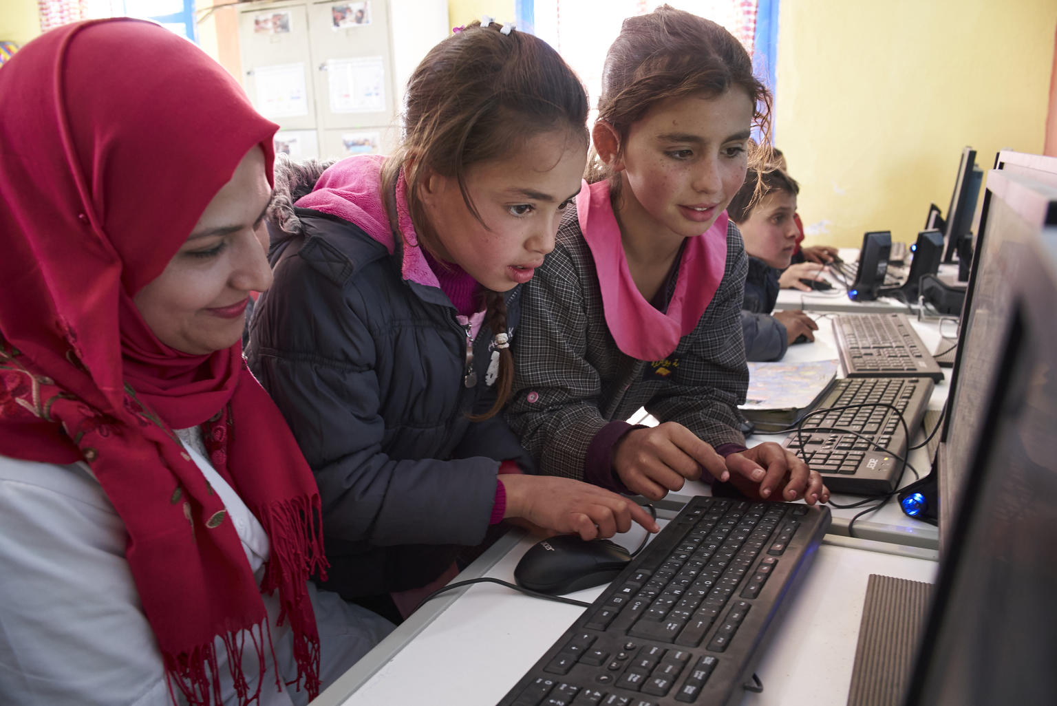 Tunisian school girls by a computer with their teacher.